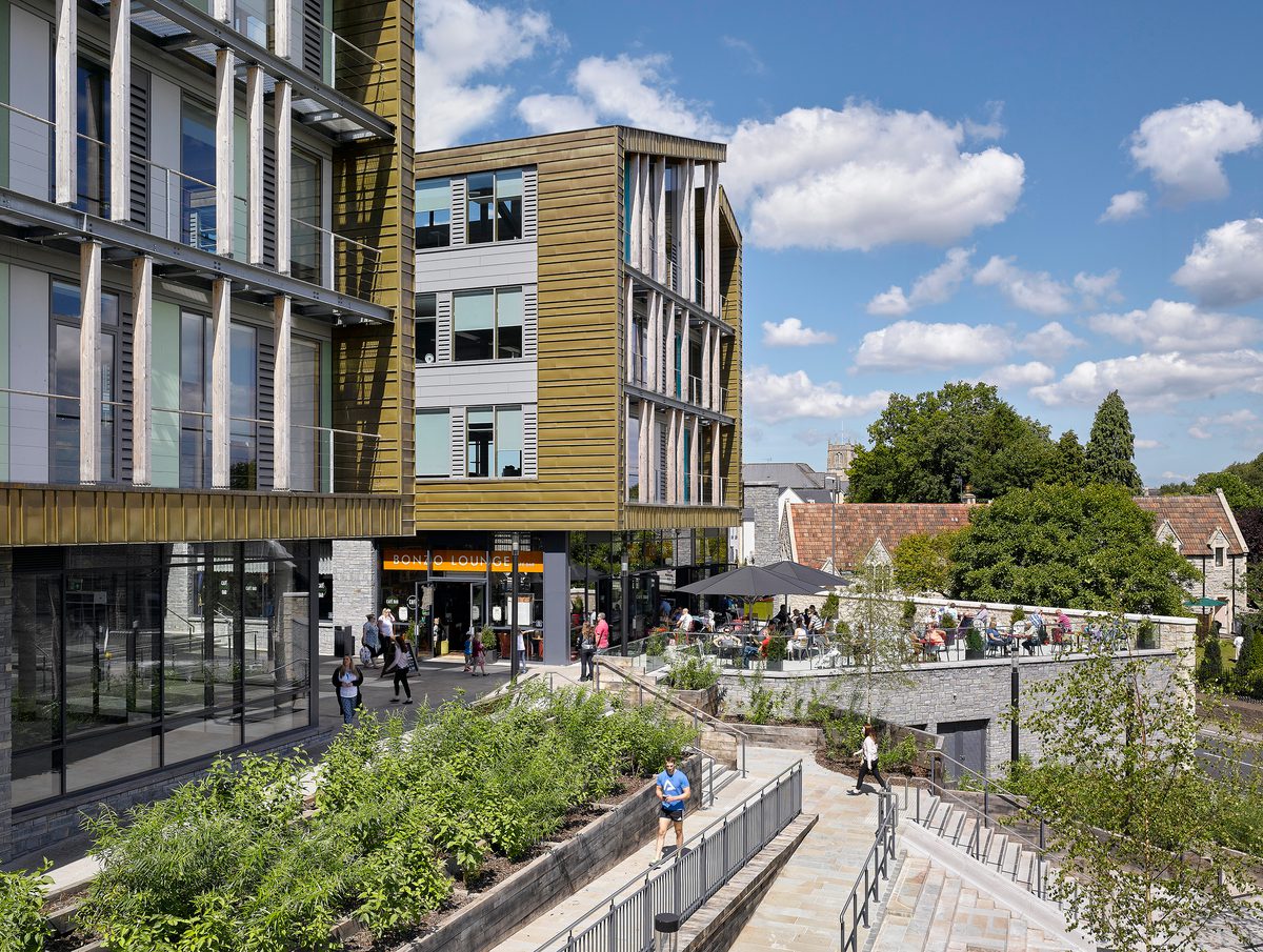 An exterior side veiw of Keynsham Civic Centre and One-Stop-Shop with people using the green spaces and surrounding public realm.