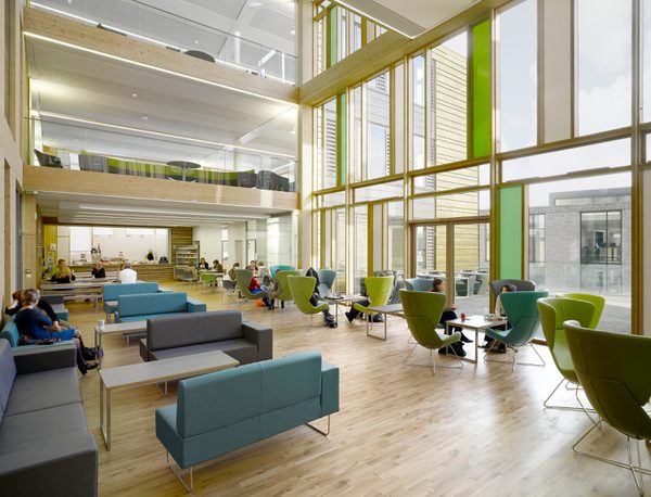 A shared working space within Keynsham Civic Centre and One-Stop-Shop, with triple height windows, mezzanine levels, wooden cladding and variety of workspaces.