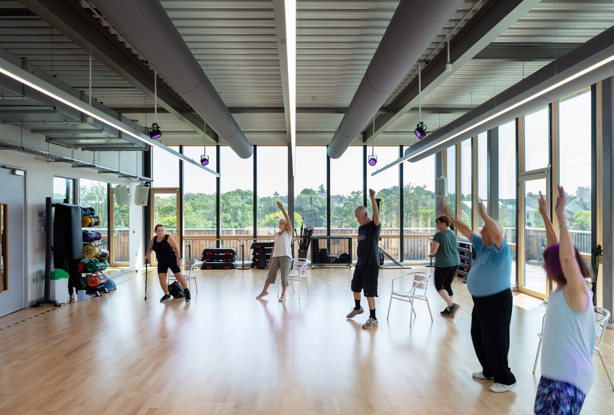 People exercising in a fitness suite within Keynsham Riverside Leisure Centre with highly glazed exterior wall.