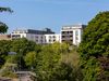 A view of Keynsham Riverside apartments in the distance, with trees and greenery in front.