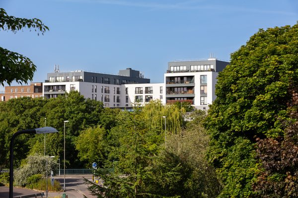 A view of Keynsham Riverside View apartments in the distance, with trees and greenery in front.