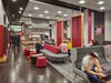People enjoying the refurbished Kings Cross First Class Lounge with red, grey and white interior decoration and furniture, and food and beverage facilities.