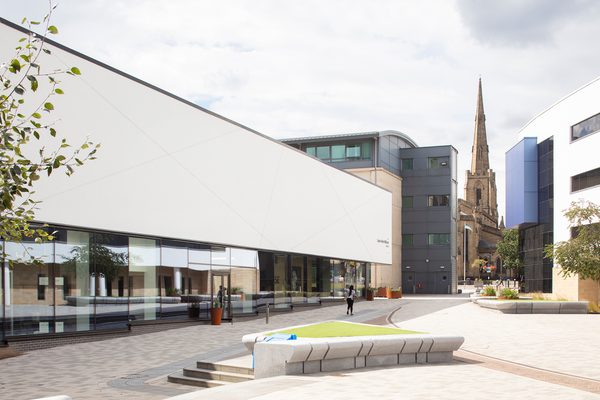 The exterior of the Laura Annie Wilson Building, with highly glazed ground floor, surrounded by landscaped public realm and city centre buildings in the background.