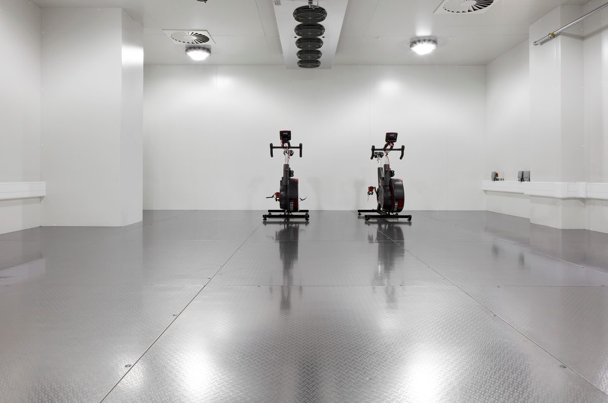 The bright interior of the environmental chamber within the Manchester Institute of Health and Performance, with exercise bikes in.