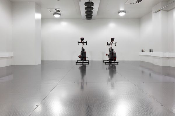 The bright interior of the environmental chamber within the Manchester Institute of Health and Performance, with exercise bikes in.