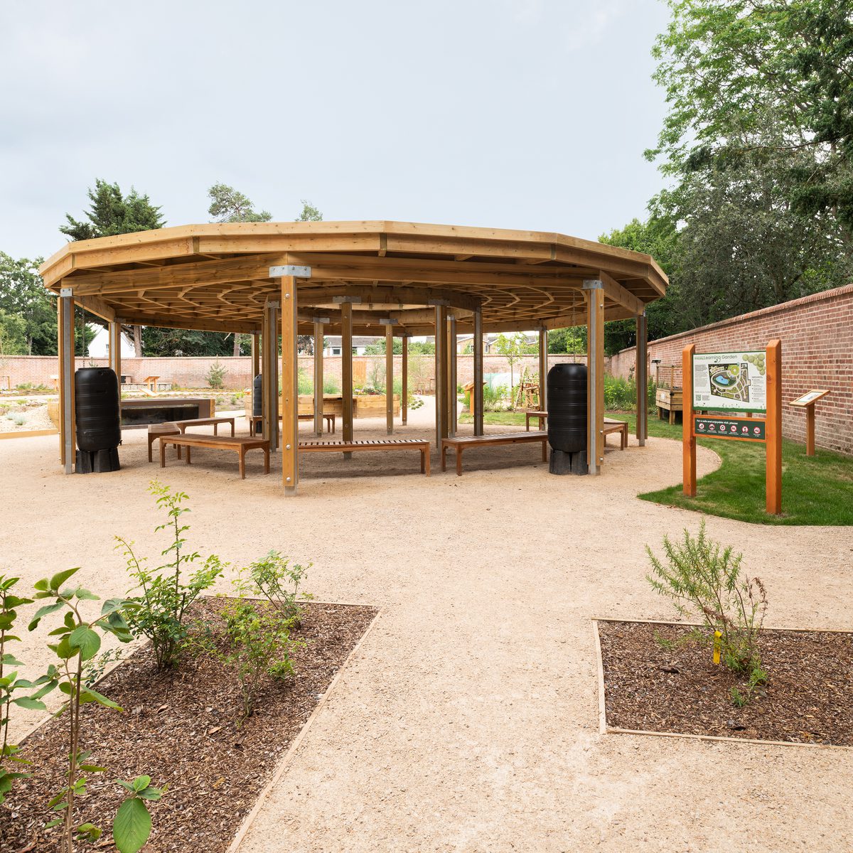 Gravel footpaths that guide visitors around the nature park and learning garden at the University of Reading with a spacious canopy in the background.