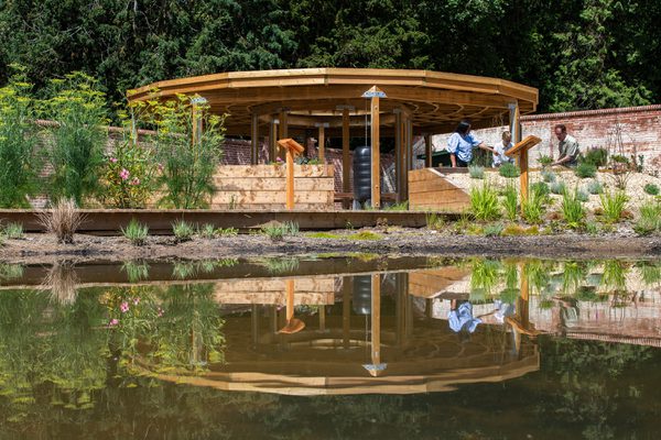 The large wooden canopy overlooking the nature pond in the foreground at the University of Reading's nature park and learning garden.