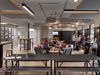People enjoying and working a variety of different workspaces, in a large, open shared social space within Origin.