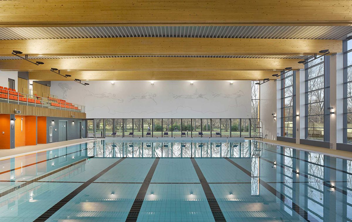 The indoor swimming pool at Places Leisure Eastleigh brightly lit with tiered seating for spectating in the background.