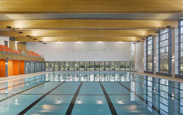 The indoor swimming pool at Places Leisure Eastleigh brightly lit with tiered seating for spectating in the background.