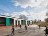Children playing within the secure outdoor play area of Highcliffe Primary School, with the colourful building exterior adjacent.