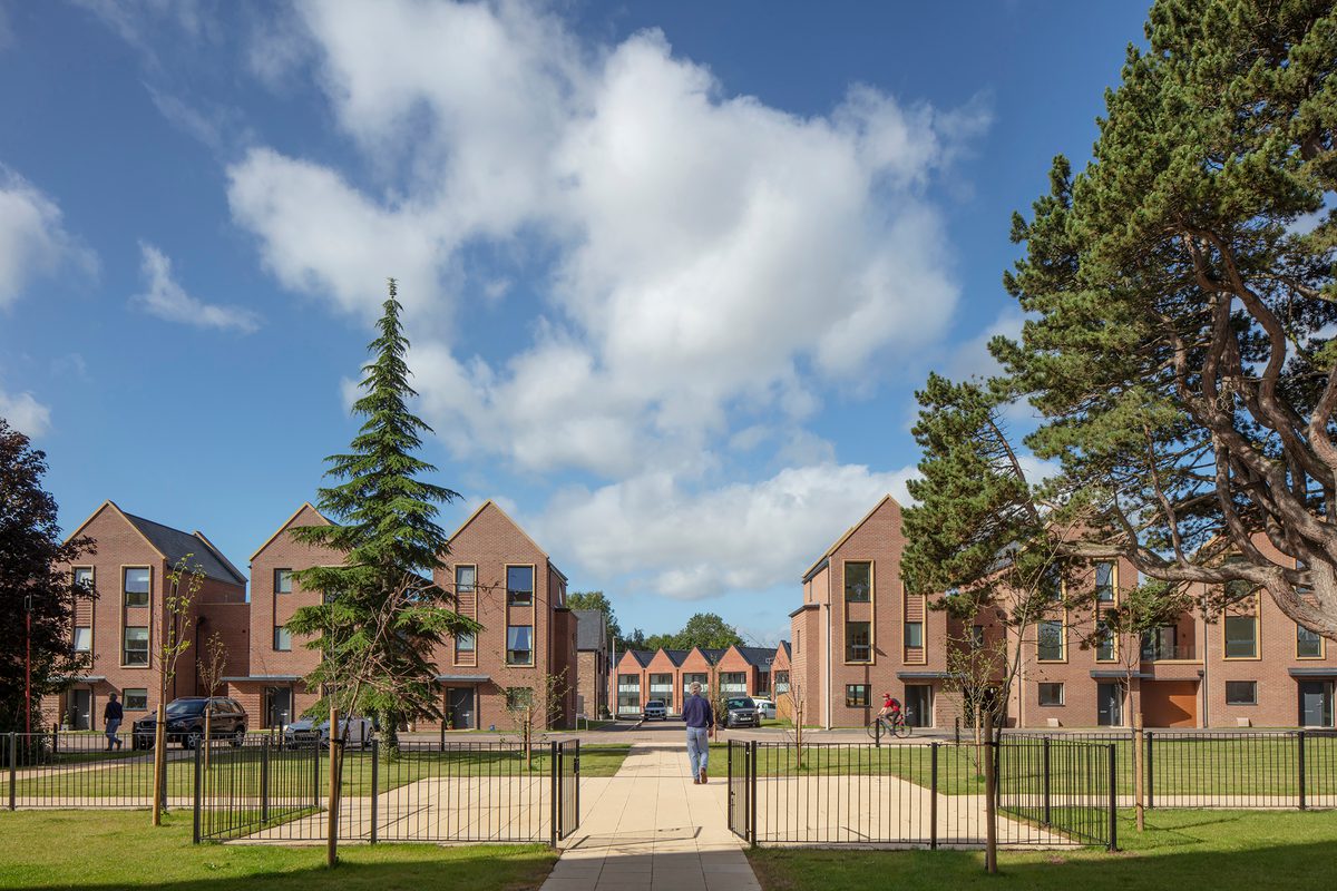 An exterior shot of the Radbrook Village development, showing the new build homes with extensive communal green space and trees in front of new build homes.