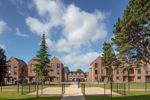 An exterior shot of the Radbrook Village development, showing the new build homes with extensive communal green space and trees in front of new build homes.