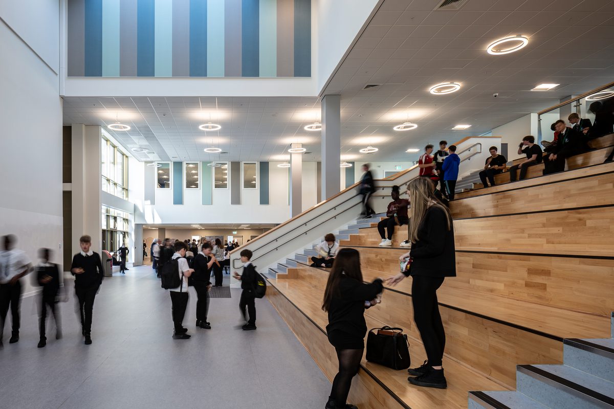 Students sitting on the Spanish Steps and using the shared space within the dining hall of the Woodmill and St Columba's RC High School.