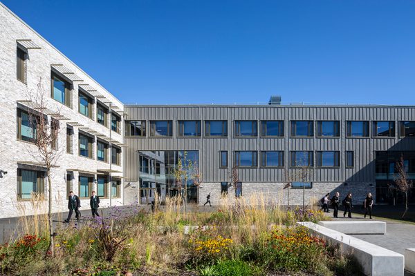 The exterior of the Woodmill and St Columba's RC High School with pupils using the landscaped social area with seating and planting.