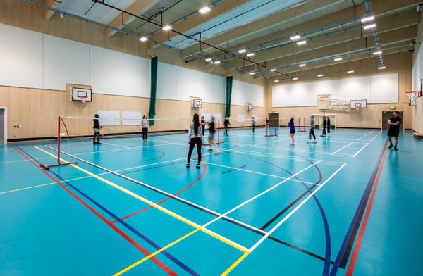Pupils playing badminton in the large two storey CLT framed sports hall at Woodmill and St Columba's RC High School.