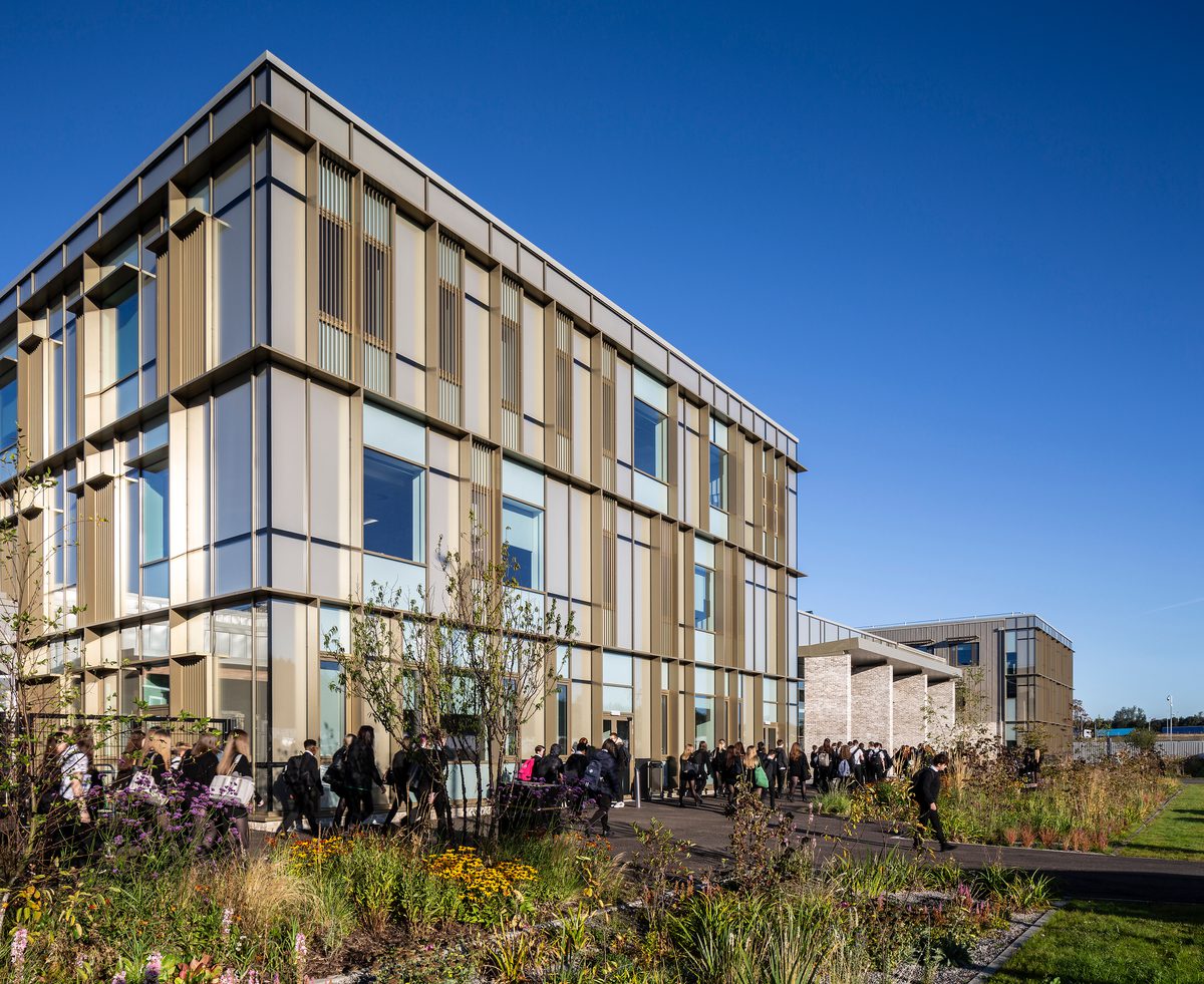 Exterior of Woodmill and St Columba's RC High School with high performance glazing, landscaped planted area and pupils in front of the building.