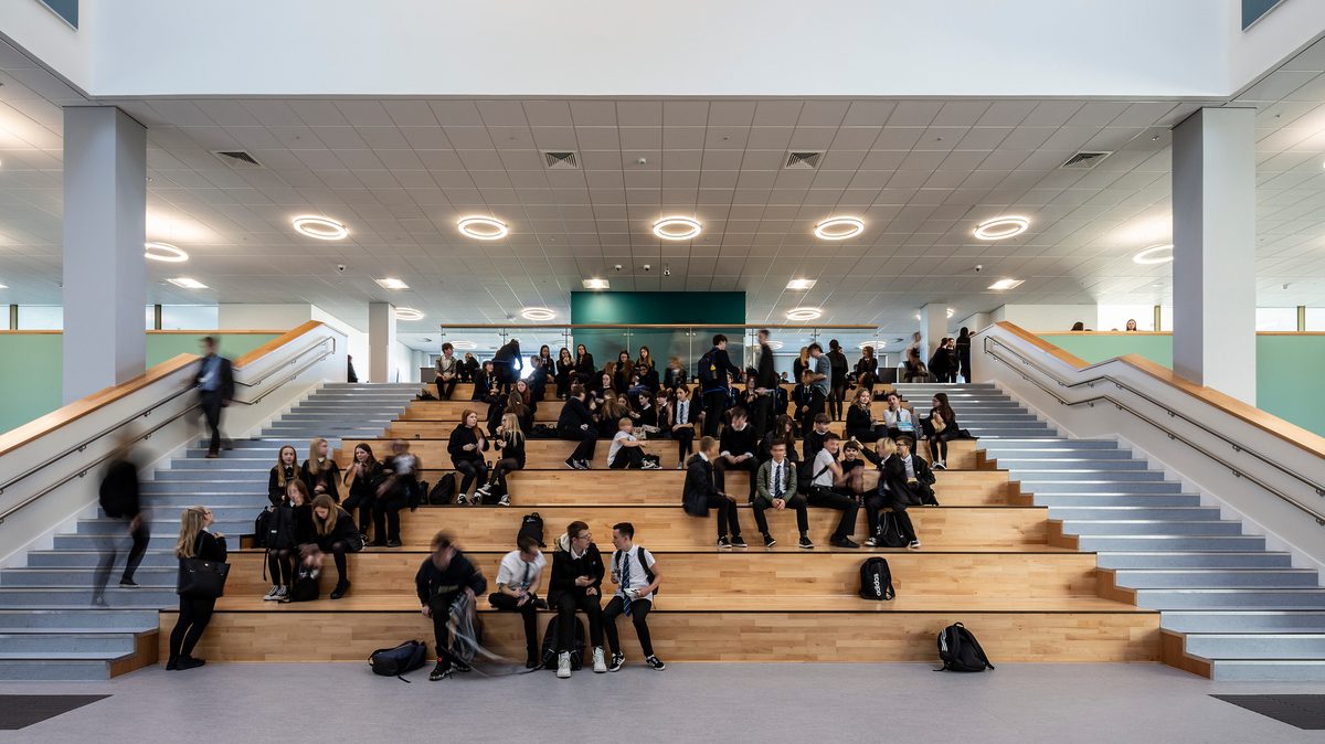 Pupils sitting on the Spanish Steps in the centre of the dining hall of the Woodmill and St Columba's RC High School.