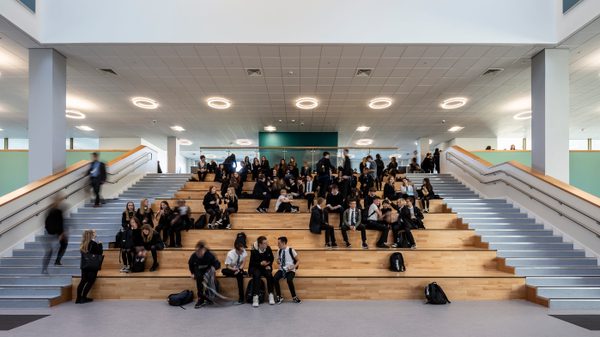 Pupils sitting on the Spanish Steps in the centre of the dining hall of the Woodmill and St Columba's RC High School.