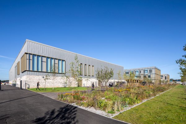 The exterior of the Woodmill and St Columba's RC High School with large amounts of planting in the landscaped communal outdoor space.