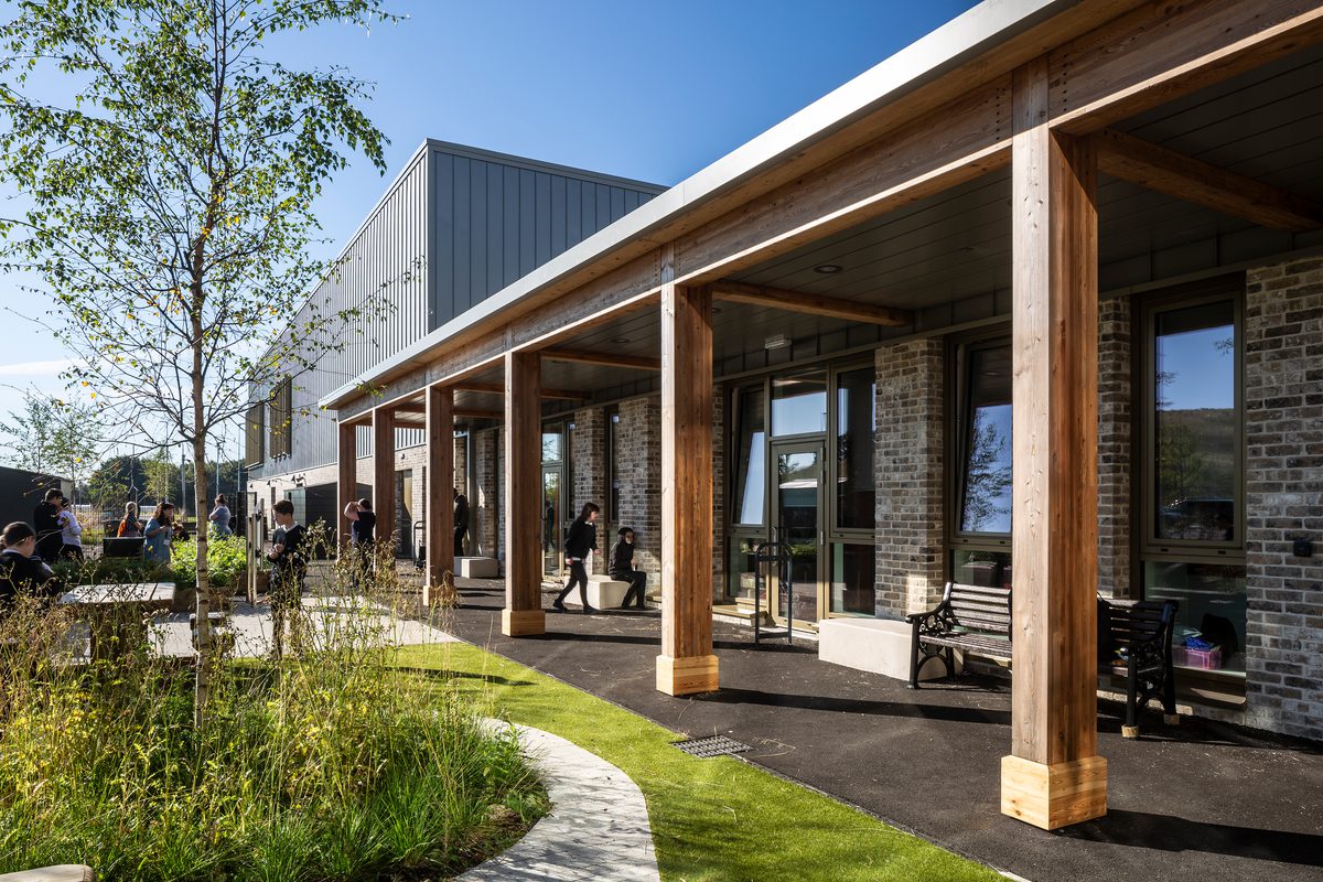 Pupils enjoying the landscaped outdoor spaces within the the Woodmill and St Columba's RC High School campus, with highly landscaped planting and a variety of seating options, with some under shelter.