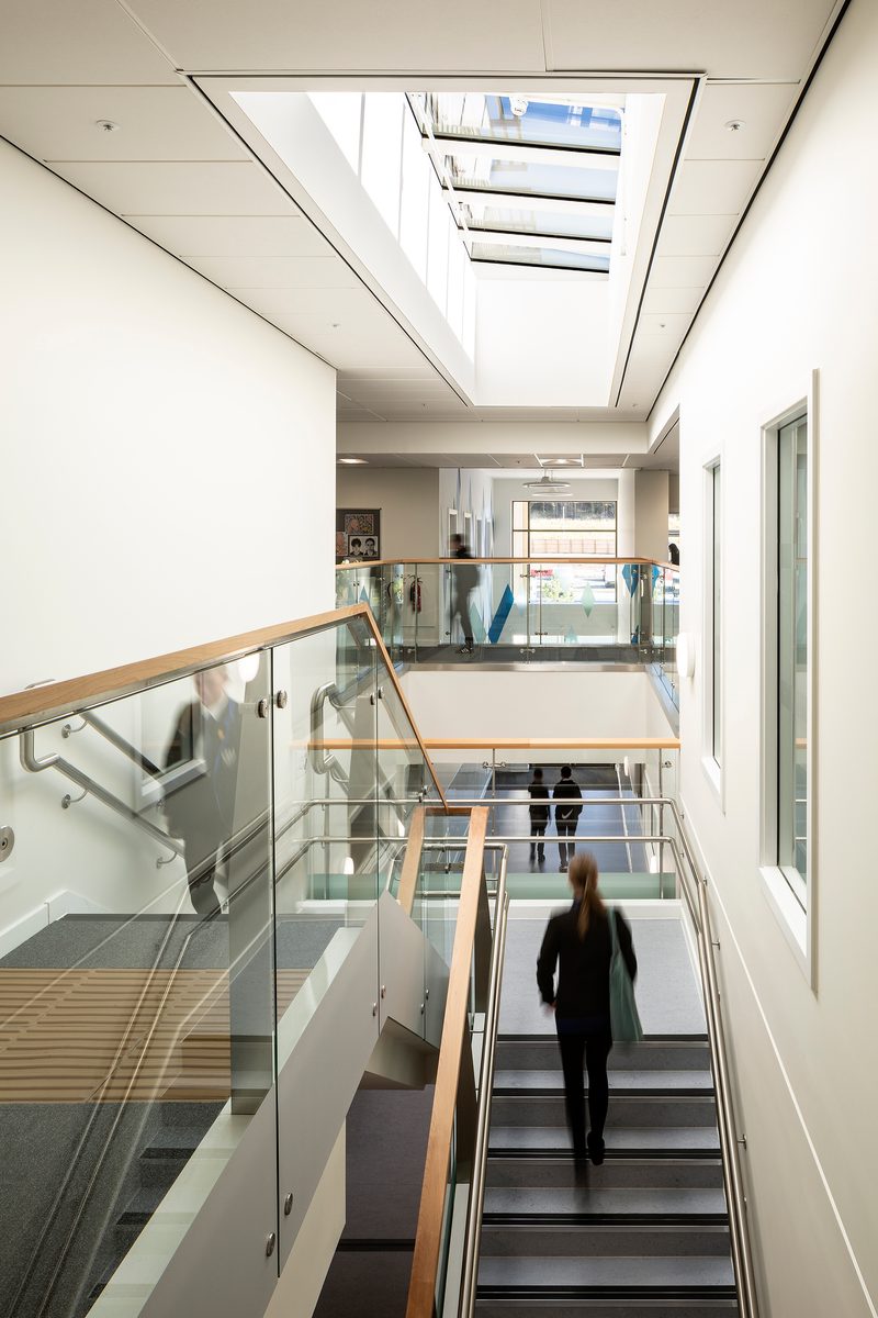Pupils walking through the bright, double height circulation space within the Woodmill and St Columba's RC High School, with glazed roof overhead.