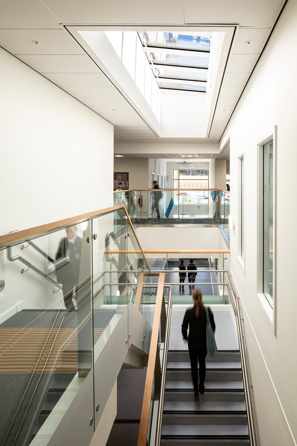 Pupils walking through the bright, double height circulation space within the Woodmill and St Columba's RC High School, with glazed roof overhead.