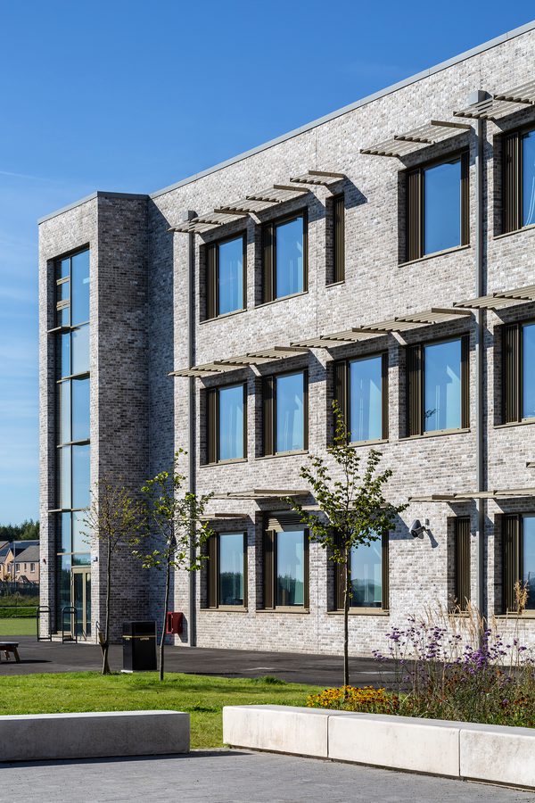 An exterior wall of the Woodmill and St Columba's RC High School, with landscaped planting in front and shading fins above each window.