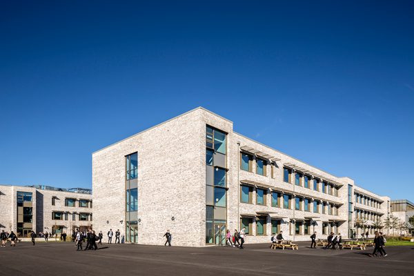 The exterior of the Woodmill and St Columba's RC High School, showing the large scale of the school, with pupils walking in the communal outdoor spaces.