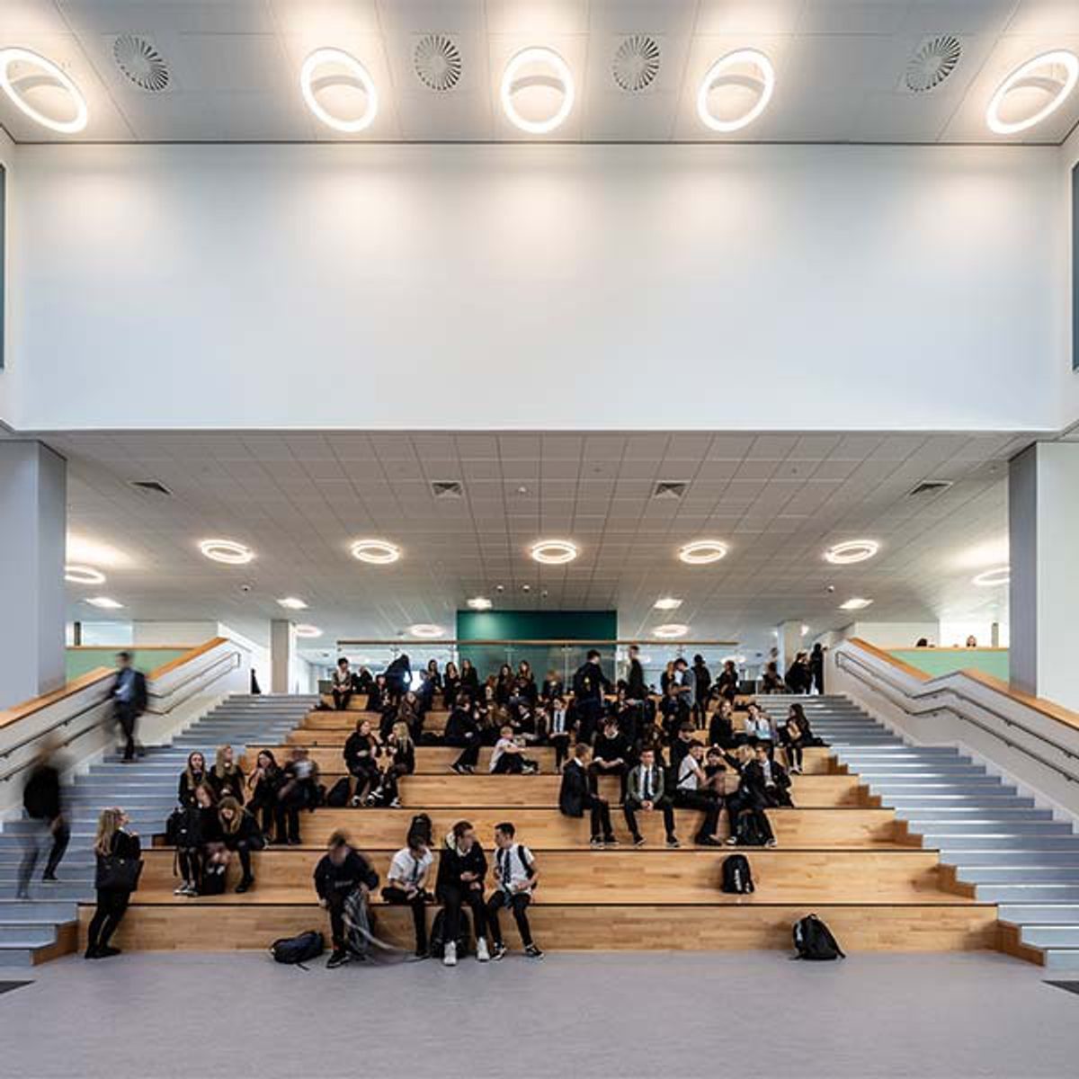 Pupils sitting on the Spanish Steps in the centre of the dining hall of the Woodmill and St Columba's RC High School.