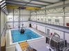An interior hall housing one of the swimming pools at the Royal Navy Centre of Maritime Training, with aircraft simulation equipment.