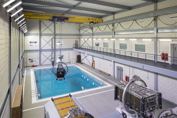 An interior hall housing one of the swimming pools at the Royal Navy Centre of Maritime Training, with aircraft simulation equipment.