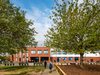 Exterior facade of Shrewsbury Academy with students walking on approach to the school's entrance and associated trees and landscape in the foreground.