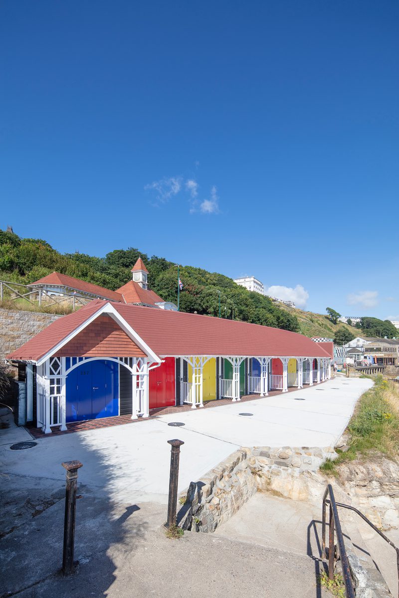 A row of rebuilt colourful beach chalets on Scarborough's South Cliff, showing their cliffside location.