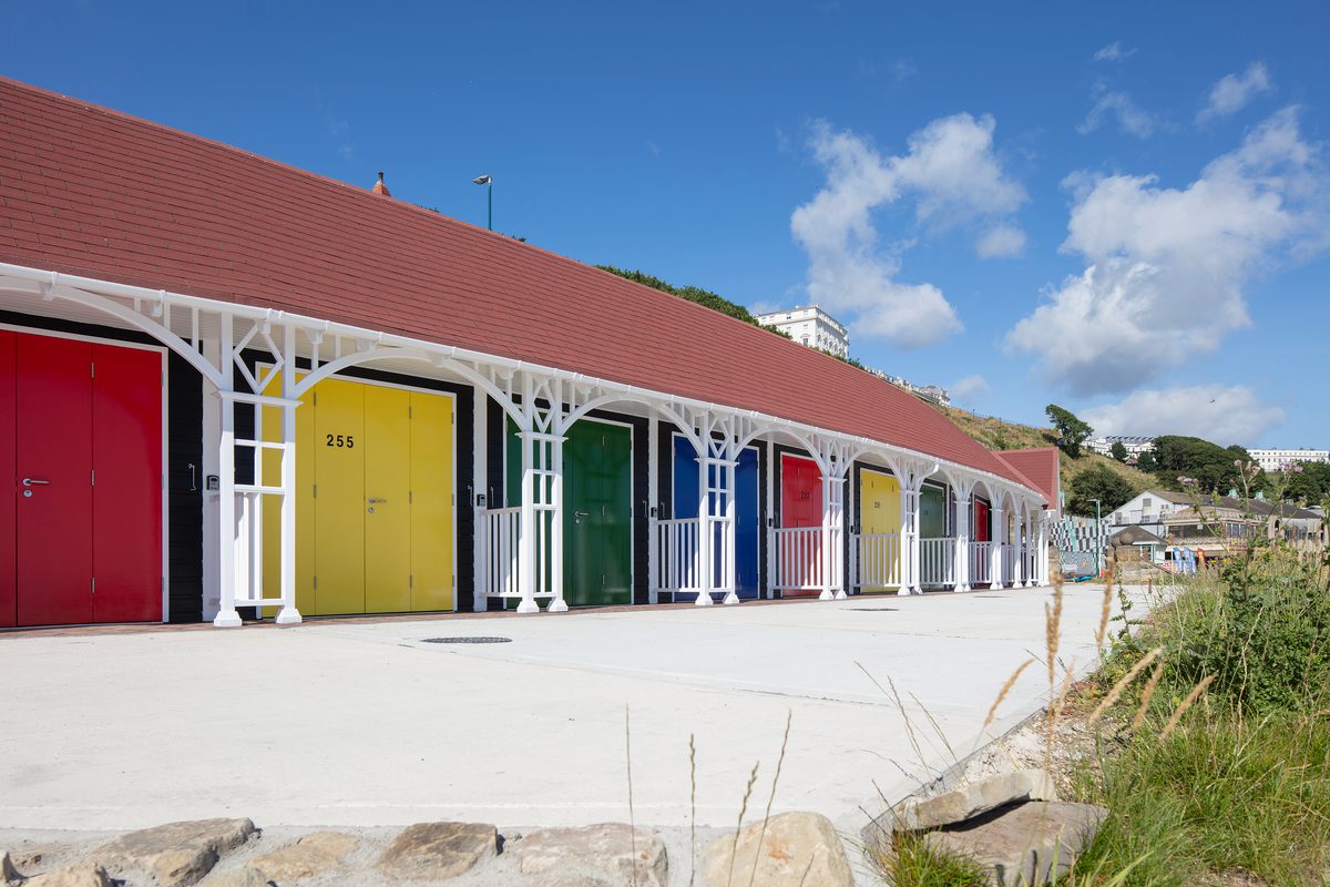 A row of rebuilt colourful beach chalets on Scarborough's South Cliff, with decorative wooden detailing.