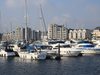 A row of sailing boats in a marina, in front of residential blocks in the background, which are part of the St Mary's Island Masterplan.