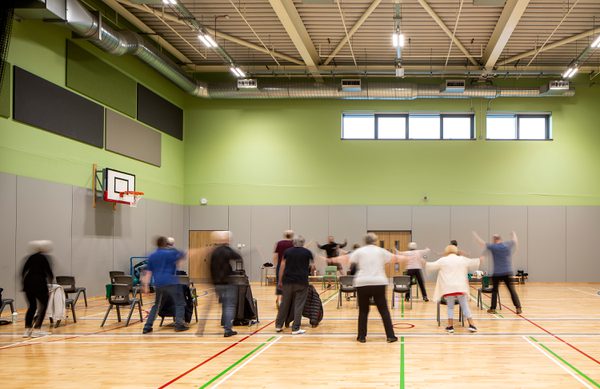 A group of people participating in a group activity inside the sports hall at Templehall Community Hub.