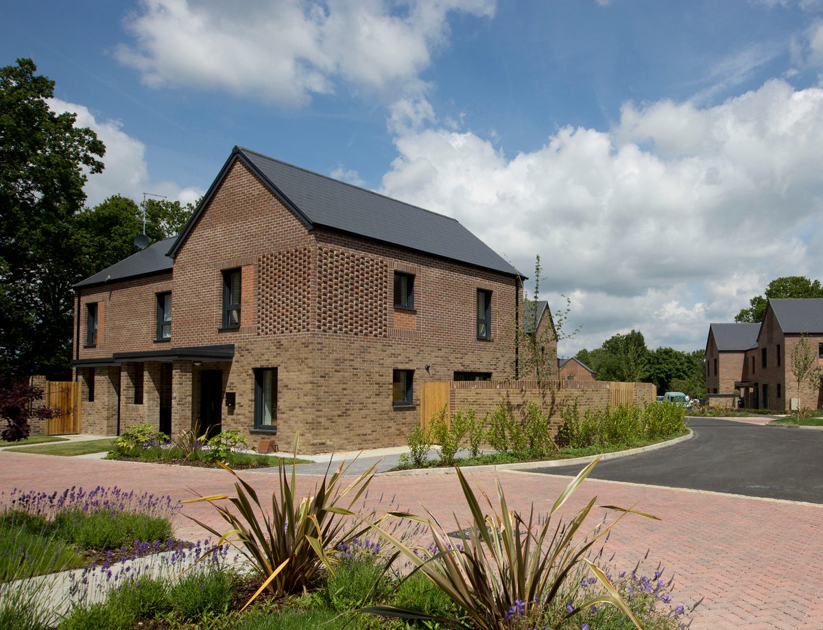 Exterior of one house in the Passivhaus residential development, The Pheasantry, surrounded by planting and space for parking.