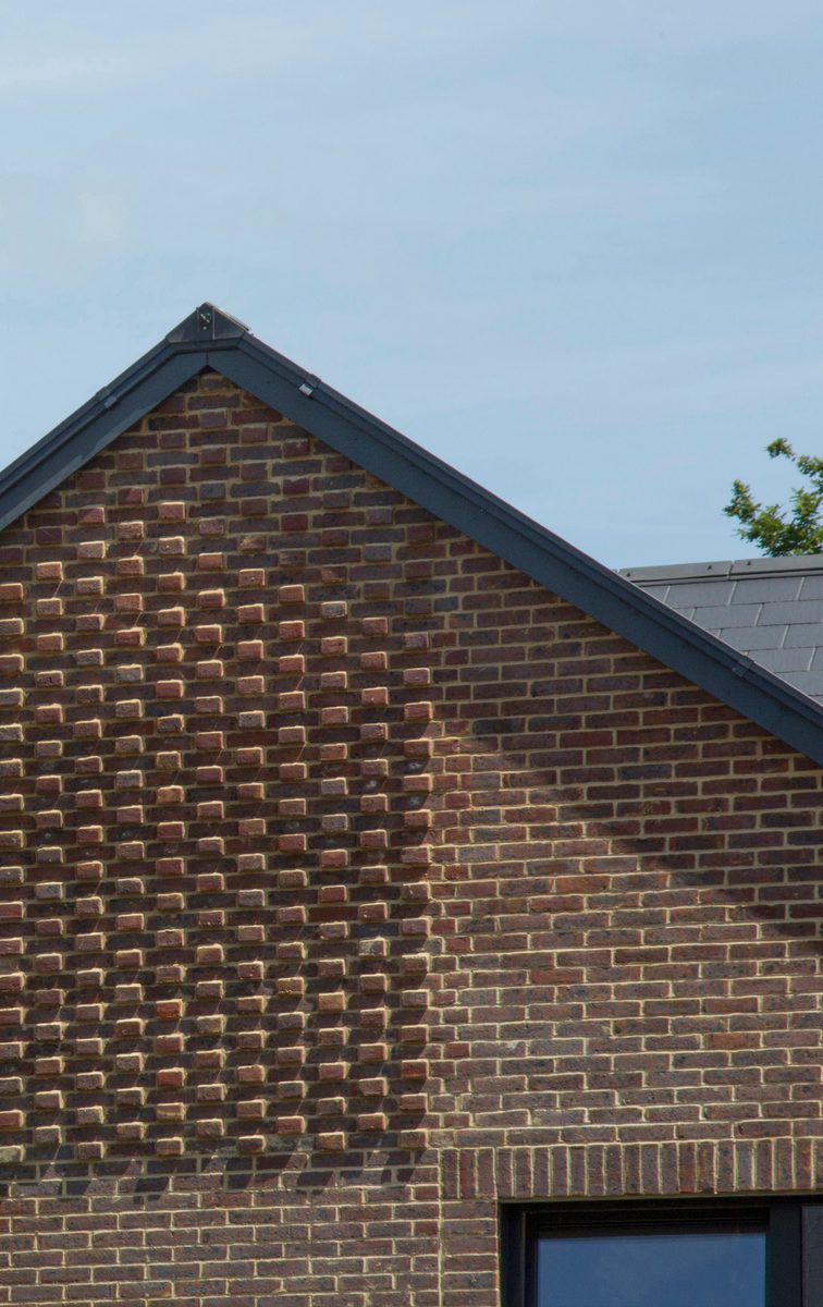 A detail shot showing the redbrick facade and gabled roof of one of the houses within the Pheasantry residential development.