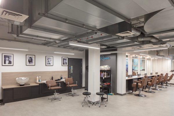 A wide shot of the barbering learning station with rows of chairs and stations, mirroring a real world salon space.