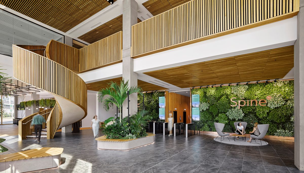 The double height, interior entrance of the Spine, with helical staircase, wooden finished and biophilic planting.