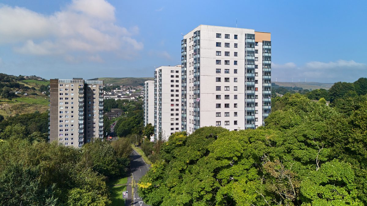 High rise tower blocks with trees against a blue sky.