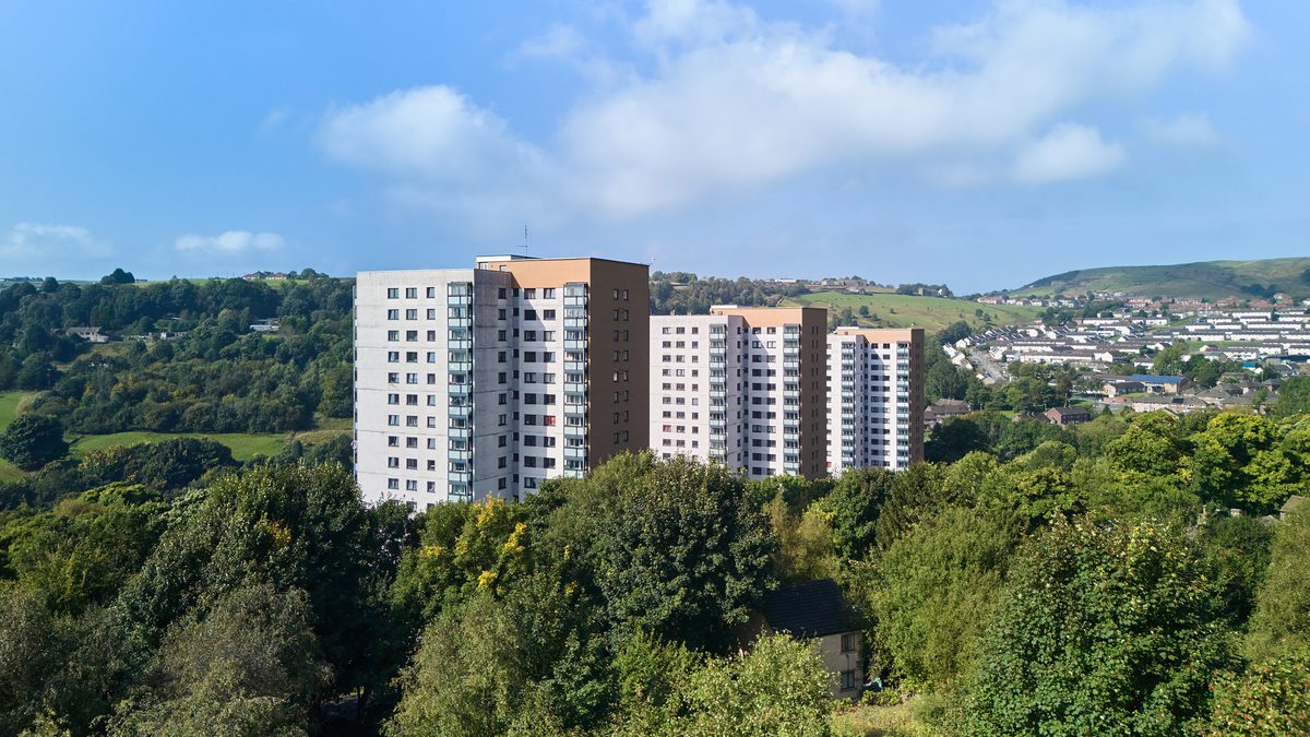 A series of high rise tower blocks against trees and greenery.