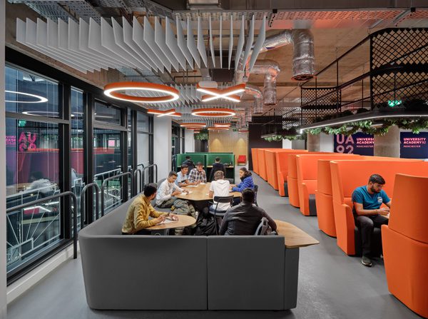 Students working together in the collaborative learning space within University Academy 92, with bespoke suspended lighting.