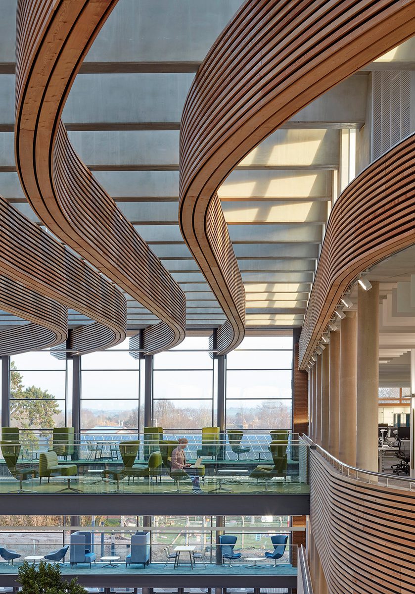 One end of the bright atrium at the UK Hydrographic Office, with an innovative wooden ceiling structure, large windows, glazed roof and breakout workspaces.