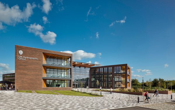 The exterior front entrance of the UK Hydrographic Office, showing the high level of glazing, bicycle storage facilities and planting surrounding the building.