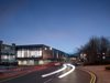 The exterior of the entirety of the Universities Centre at dusk, showing its floor to ceiling windows and prominent location.