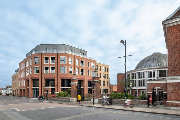 The redbrick exterior of the Livewell Hub at Victoria Square, showing its town centre location, with pedestrians walking in front.